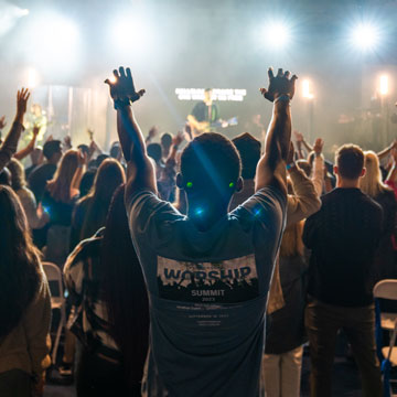 concert crowd worshiping with hands in the air