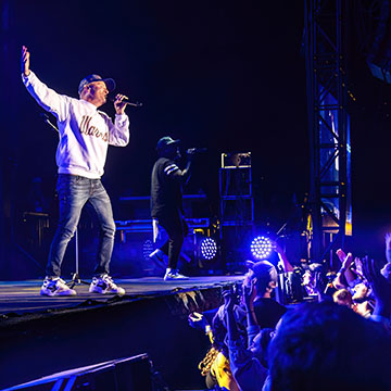 performer on stage and people in the crowd singing at concert