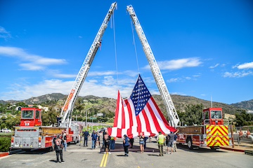 Service members attaching an American flag to fire truck ladders